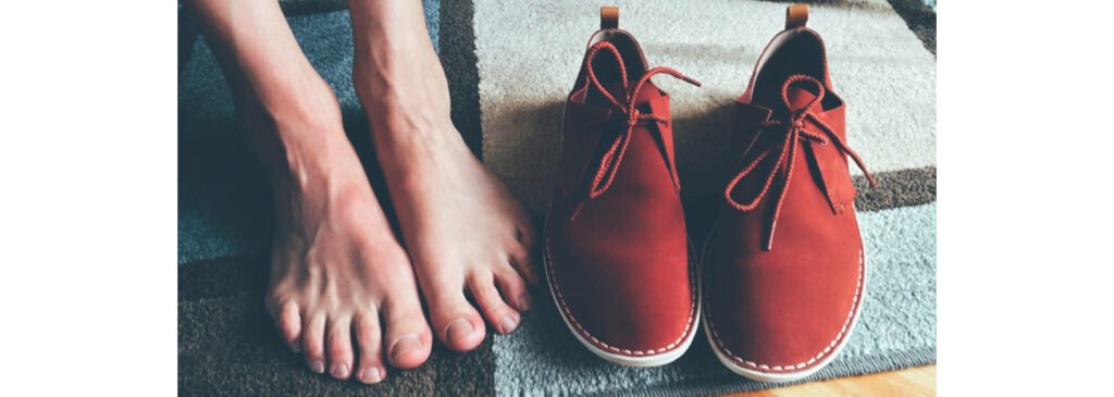 Pés descalços ao lado de um par de tênis vermelho